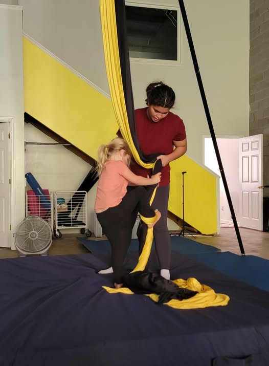 Coach guiding a student on aerial silks at Ducking Gravity